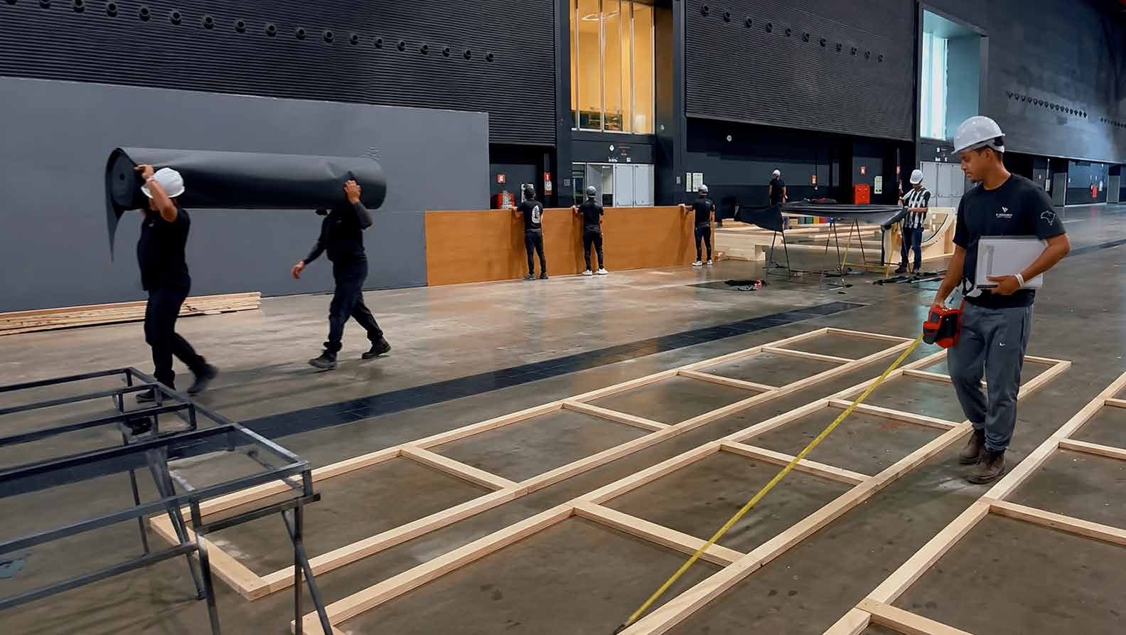 Montagem de piso cenográfico dentro de um pavilhão de eventos