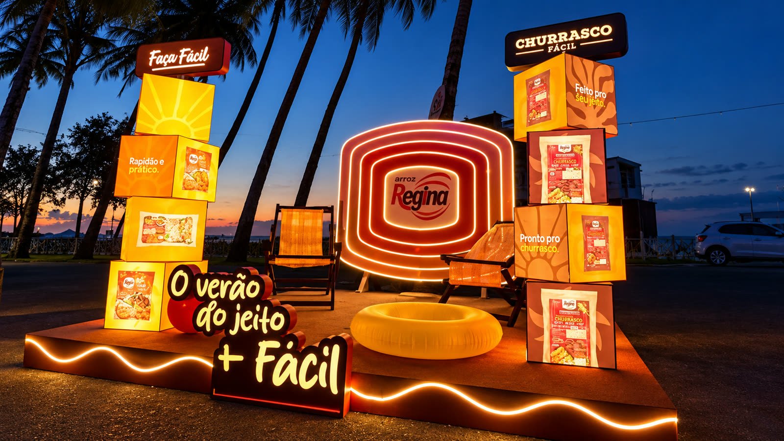 Cenografia da Regina à noite na praia, com caixas gigantes iluminadas e a frase O verão do jeito + fácil