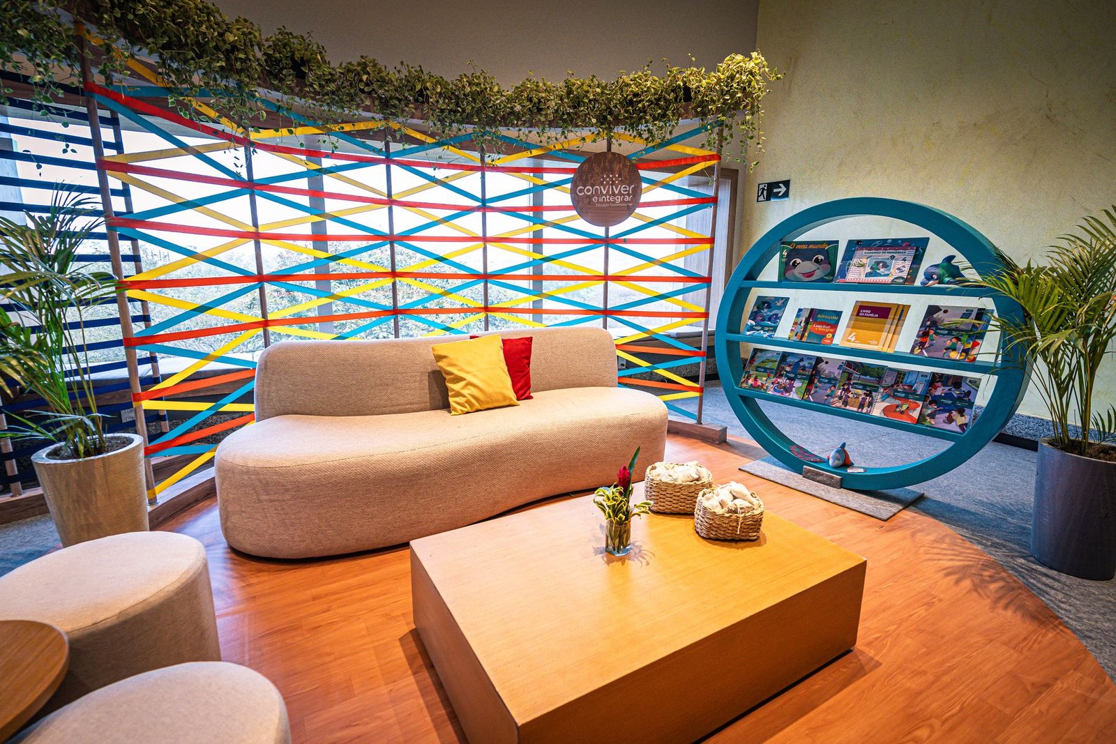 Espaço Conviver e Integrar com teia de fitas coloridas e estante circular