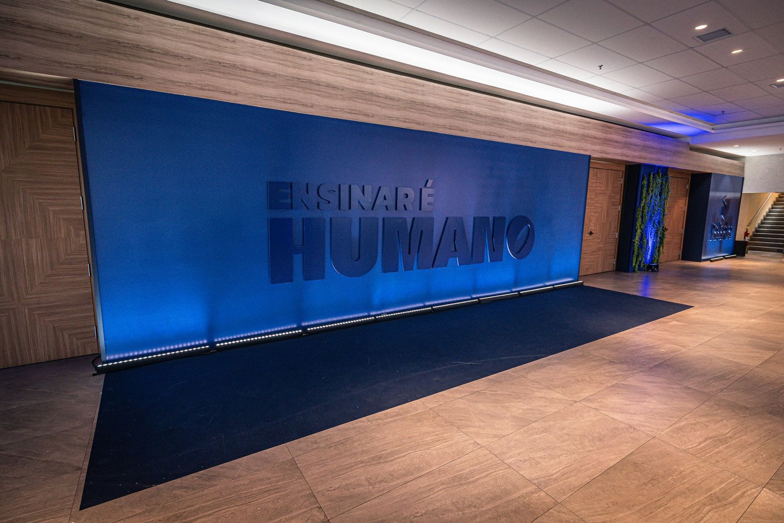 Painel iluminado com a frase Ensinar é Humano em corredor