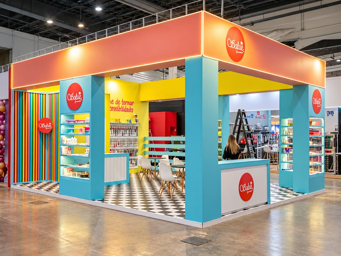 Stand colorido da Babie com colunas azul-turquesa, testeira laranja e piso xadrez
